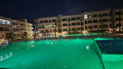 a large swimming pool in front of a building at night at Appartement à louer Eden Mansouria Residence in Mansouria