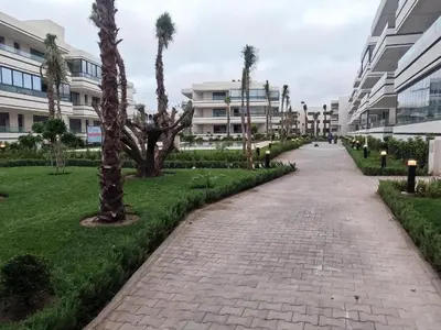 a brick pathway with palm trees and buildings at Appartement à louer Eden Mansouria Residence in Mansouria