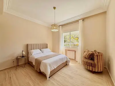 a bedroom with a bed and a chair and a window at Luxurious Ocean View Villa Ain Diab in Casablanca