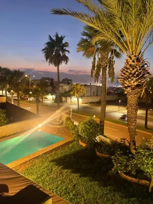 a resort with a pool and palm trees at night at Luxurious Ocean View Villa Ain Diab in Casablanca