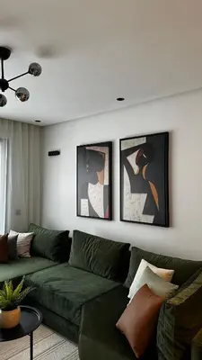 a living room with a green couch and framed pictures at studio luxe rooftop & gym quartier des princess in Casablanca