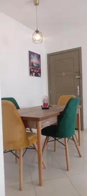 a dining room table with green chairs in a room at Cosy studio dar bouazza in Casablanca