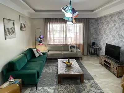a living room with a green couch and a television at Magnifique Appartement familial avec piscine in Mohammedia