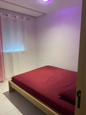 a red bed in a white room with a window at Résidence Picasso in Casablanca