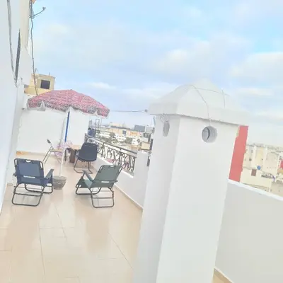 a balcony with chairs and a table and an umbrella at Private Room in Shared Apartment step by mosquée Hassan II in Casablanca