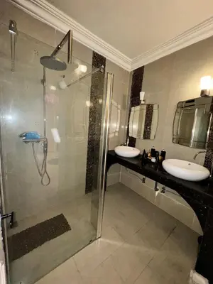 a bathroom with a glass shower and two sinks at Ideal appartement CAN2025 Grand Stade Rabat in Temara