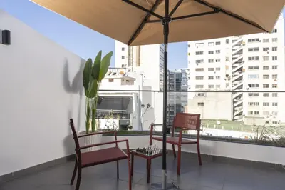 a balcony with a table and chairs and an umbrella at Bright Modern Studio, Gauthier in Casablanca