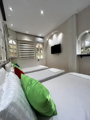 a bedroom with three beds and a tv on the wall at Sympa appartement corniche in Casablanca