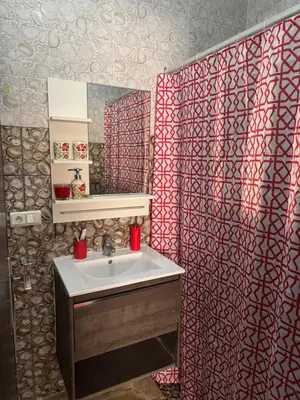 a bathroom with a sink and a red and white shower curtain at Apartment dar bouazza in Dar Bouazza