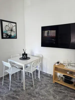 a white table and chairs in a room with a tv at Apartment dar bouazza in Dar Bouazza