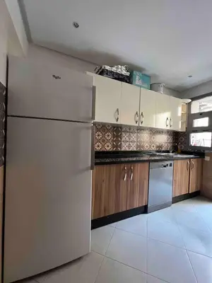 a kitchen with a white refrigerator and wooden cabinets at Appartment Maarif proche toutes commoditées in Casablanca