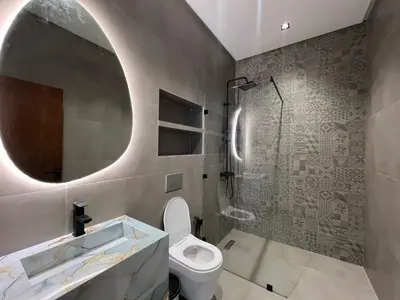 a bathroom with a toilet and a shower with a mirror at Ferme villa in Skhirat