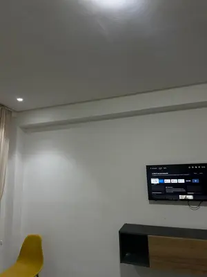 a room with a tv on the wall with a chair at App 8 in Rabat
