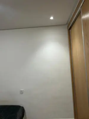 a bedroom with a white wall and a wooden door at App 8 in Rabat