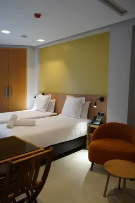 a hotel room with two beds and a chair at Agdotel Urban Suites in Rabat