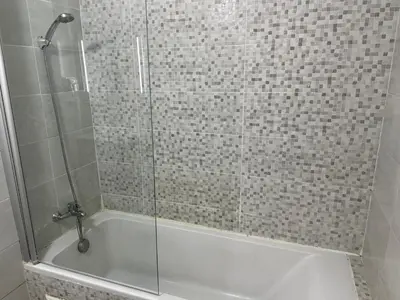 a shower with a glass door and a tub at Studio Stade Morocco for family in Mohammedia