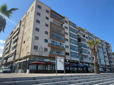 a large building on a street with a palm tree at Studio Stade Morocco for family in Mohammedia