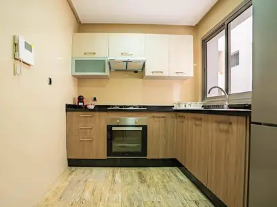 a kitchen with wooden cabinets and a stove top oven at Casablanca Breeze - By AppartAli in Casablanca