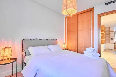 a bedroom with a large white bed with a wooden headboard at Oceanfront 2BR by Hassan II Mosque in Casablanca