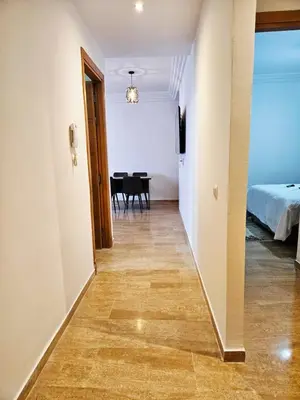 a corridor of a room with a bed and a table at Sunset Ocean View in Rabat