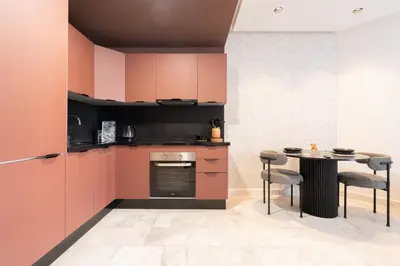 a kitchen with pink cabinets and a table with chairs at 1BR Private Terrace Parking Gym in Casablanca