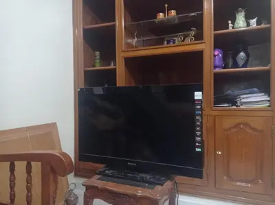 a large flat screen tv in a wooden cabinet at 2 bedroom apartment and living room with small terrace in Skhirat