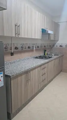 a kitchen with wooden cabinets and a counter top at Baya Residentie in Temara
