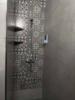 a bathroom with a shower with a tile wall at Cozy getaway for a perfect stay in Rabat