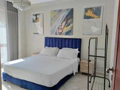 a bedroom with a bed with a blue headboard and paintings at Camera a 2 minuti dal mare e la mosquee Hassan 2 in Casablanca-Port