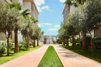 a walkway through a park with trees and a fountain at Elegant apartment in Nouaceur, Close to Airport in Nouaseur