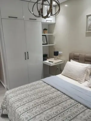 a bedroom with a bed and a desk and a chandelier at Sea view Apart Rabat in Rabat