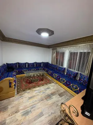 a living room with a blue couch and a table at Appartement idéal pour la CAN à 5 min du stade Moulay Abdellah in Rabat