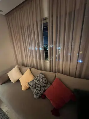 a couch with pillows sitting in front of a window at Appartement cosy 2 chambres à Agdal, à 5 min de la Gare in Rabat