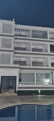 a tall white building with a parking lot in front of it at Appt Mansbay beach in Mansouria