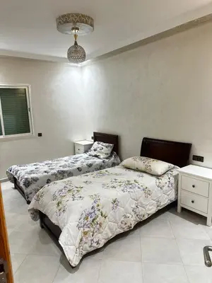 a bedroom with two beds and a table and a lamp at Appartement central à Témara, trés proche de Rabat Av Tarik Ibn Zaid in Temara