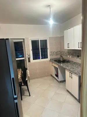 a kitchen with white cabinets and a table and a chair at Appartement central à Témara, trés proche de Rabat Av Tarik Ibn Zaid in Temara