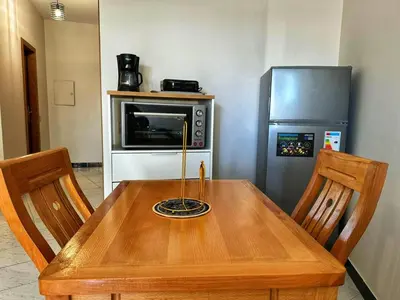 a wooden table with two chairs and a refrigerator at Studio Premium à Agdal , Confort et emplacement in Rabat