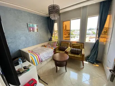 a bedroom with a bed and a chair and a table at Appartement prestigieuse en plein cœur de Hay Riad et près du stade Moulay Abdallah in Rabat