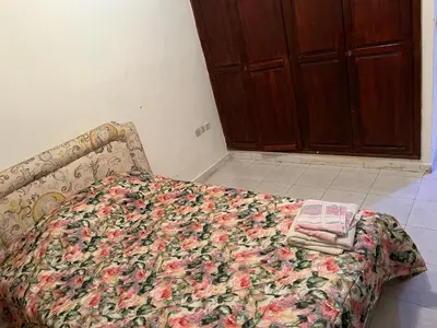 a bedroom with a bed with a floral blanket on it at Location des appartements souf in Temara