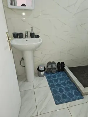 a bathroom with a sink and shoes on a blue rug at Superbe studio a avenue france agdal in Rabat