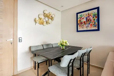 a dining room with a black table and chairs at Cosy 2 Bedrooms Skhirat Residence in Skhirat