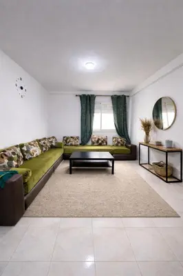 a living room with a green couch and a table at Appartement Bouskoura 15 min de l'aéroport mohamed 5 in Casablanca