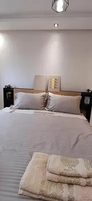 a bedroom with two beds with white sheets and pillows at Apartment in Bouznika with pool in Bouznika