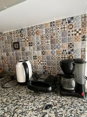 a kitchen counter with two coffee makers and a tiled wall at Apartment in Bouznika with pool in Bouznika