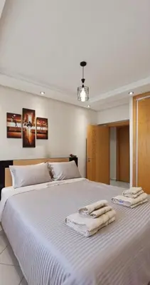 a bedroom with a large white bed with towels on it at Apartment in Bouznika with pool in Bouznika