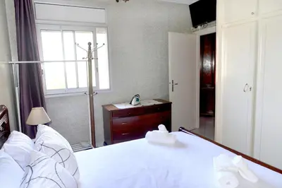 a bedroom with a white bed and a window at Appartement familial convivial in Rabat