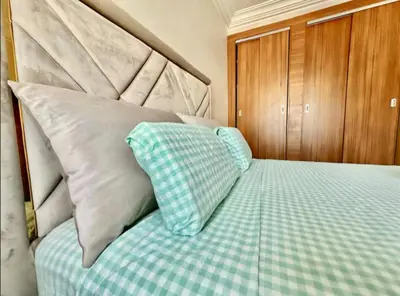 a bed with a green checkered sheets and pillows at Rome Avenue Luxury Residence, 3 Chambres in Casablanca