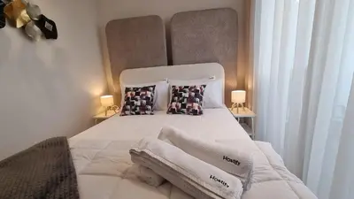 a bedroom with a white bed with two lamps at Suite Cozy Design Suite Maarif, Close to Ain Diab in Casablanca