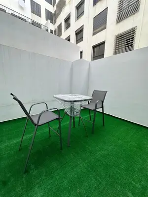a table and chairs on a green floor with a building at Modern Apartment in Maarif Princess in Casablanca