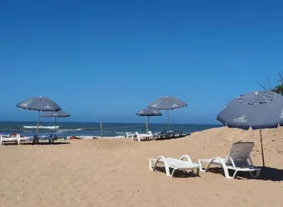 a group of chairs and umbrellas on a beach at Diha Appartement in Sidi Rahal